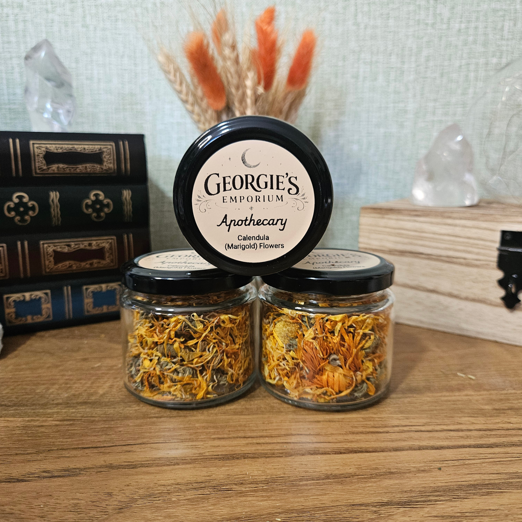 Glass apothecary jar of dried Calendula flowers displayed with natural botanicals