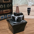 Black ceramic cascade backflow incense burner with incense cone and white smoke flowing down the tiered design.