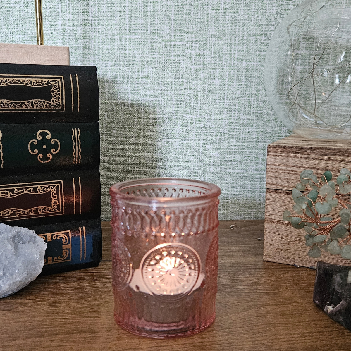 Pink embossed glass tealight holder with decorative vintage-style pattern and lit tealight candle.