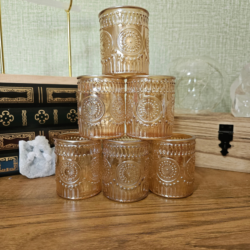 Amber glass tealight holder with embossed vintage pattern and lit candle
Set of amber glass tealight holders with decorative embossed design