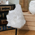 Natural Brazilian clear quartz crystal cluster on a black metal display stand, 130mm tall