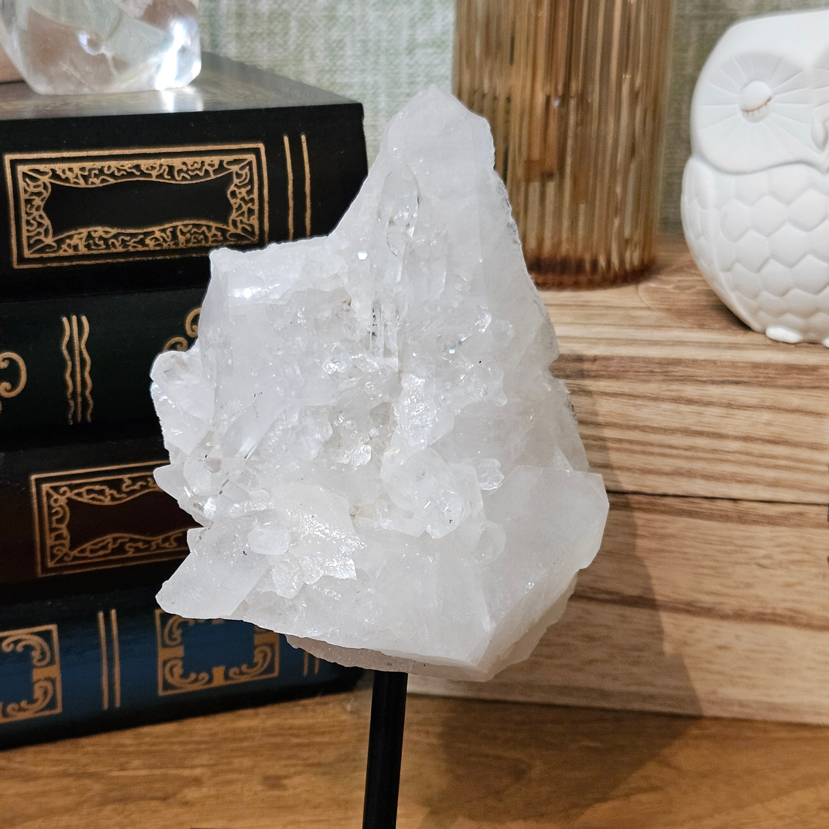 Natural Brazilian clear quartz crystal cluster on a black metal display stand, 130mm tall