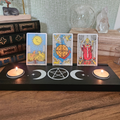 Black wooden Triple Moon tarot card holder with pentacle design, three tarot cards and two tealight holders.