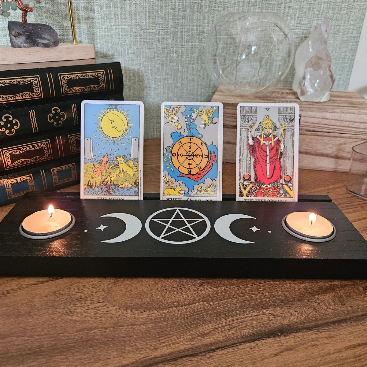 Black wooden Triple Moon tarot card holder with pentacle design, three tarot cards and two tealight holders.