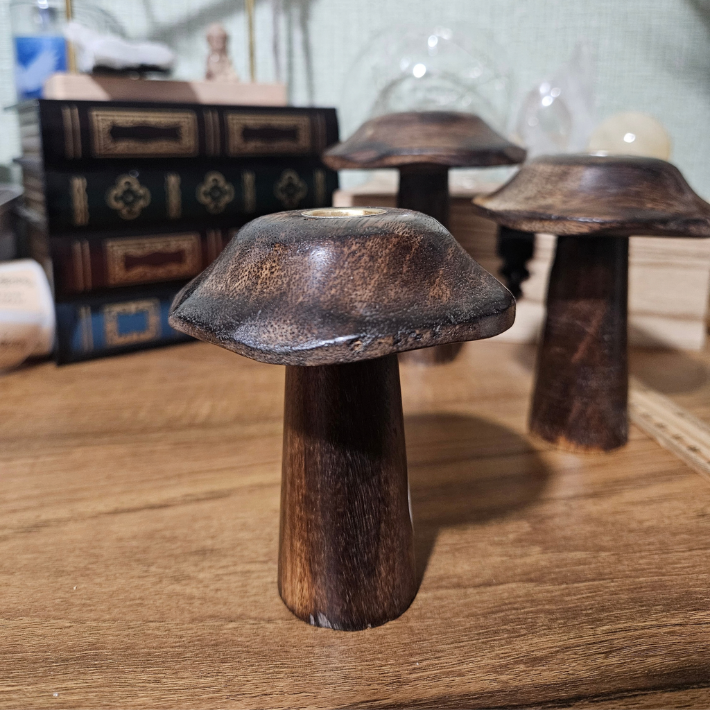 Set of three dark wooden mushroom-shaped incense cone holders in graduating sizes with brass-toned holders.