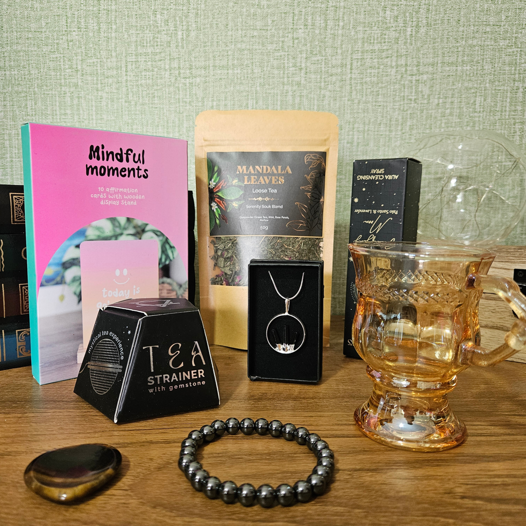 Protect Your Peace Corporate Survival Kit gift box with crystal jewellery, Tiger's Eye worry stone, aura spray, tea, smoky glass mug, Smoky Quartz tea infuser and affirmation cards.