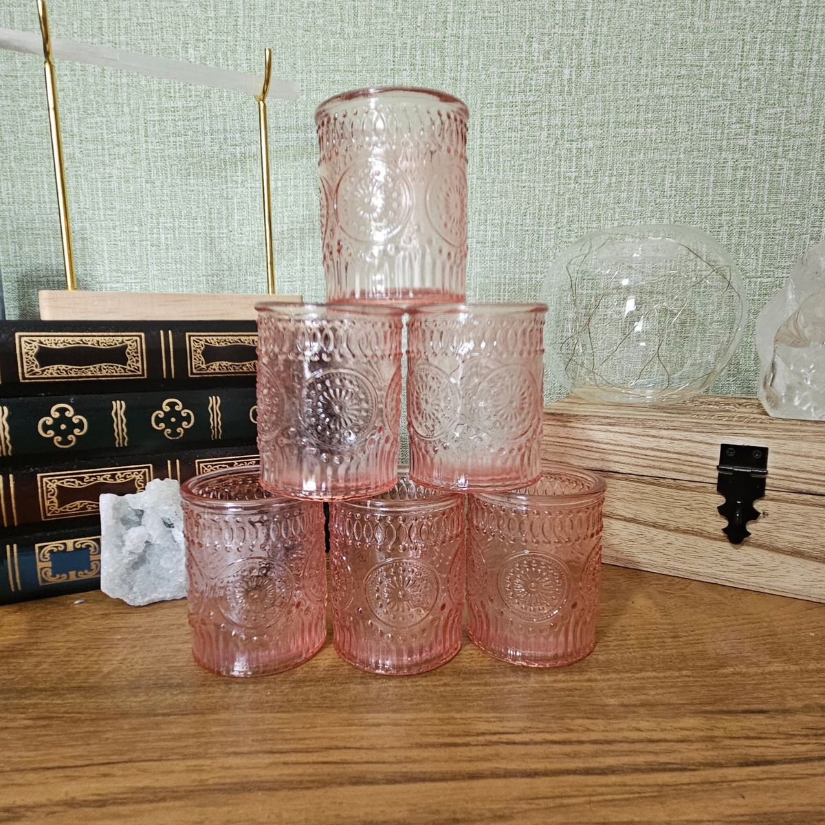 Pink embossed glass tealight holder with decorative vintage-style pattern and lit tealight candle.