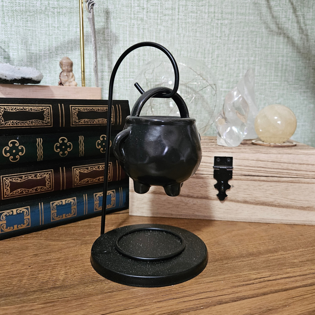 Black hanging cauldron wax melt and fragrance oil burner on a metal stand.