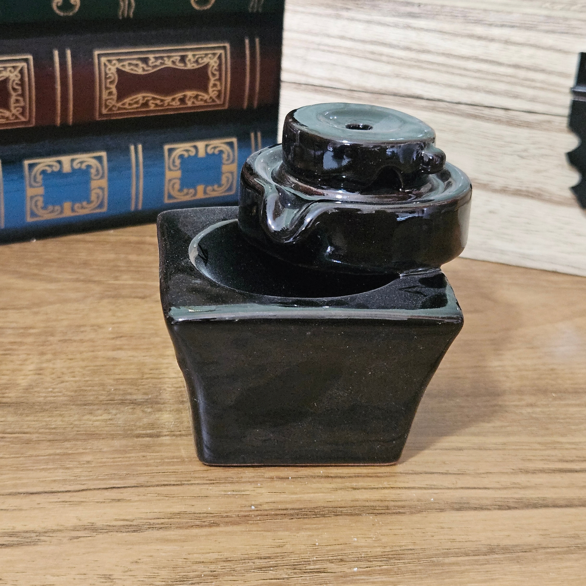 Black ceramic cascade backflow incense burner with incense cone and white smoke flowing down the tiered design.
