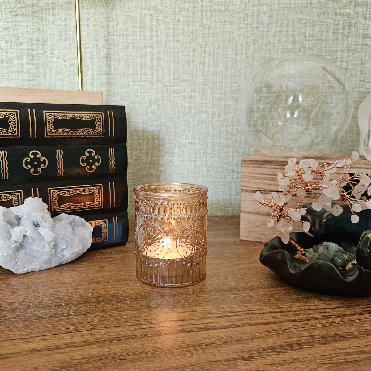 Lit amber glass tealight holder styled with crystals and home decor