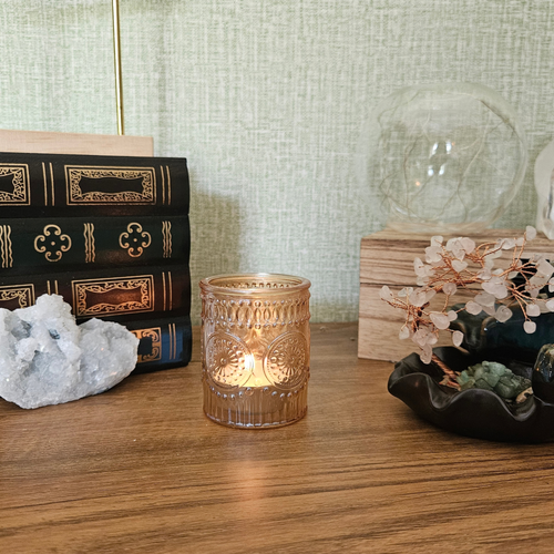 Lit amber glass tealight holder styled with crystals and home decor