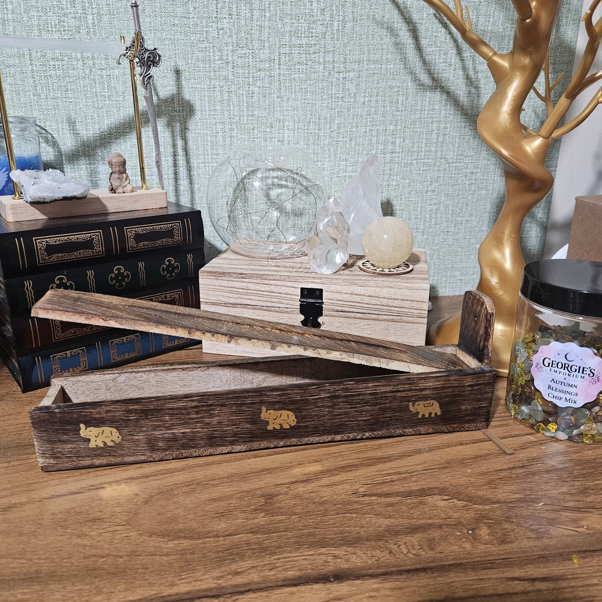 Dark wooden incense stick holder and storage box decorated with small brass elephant inlays.