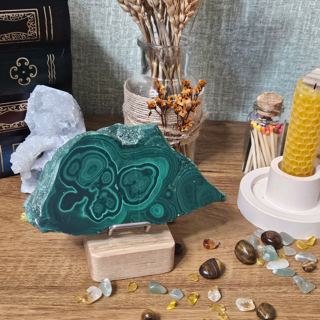 Natural 150g Malachite slice displayed on a wooden stand with distinctive dark and bright green banding.