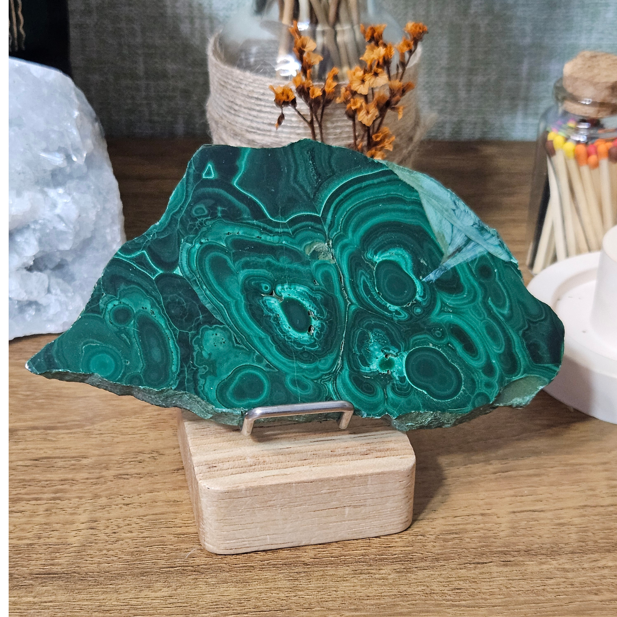 Close-up of polished natural Malachite slice showing vivid green concentric rings and swirling patterns.