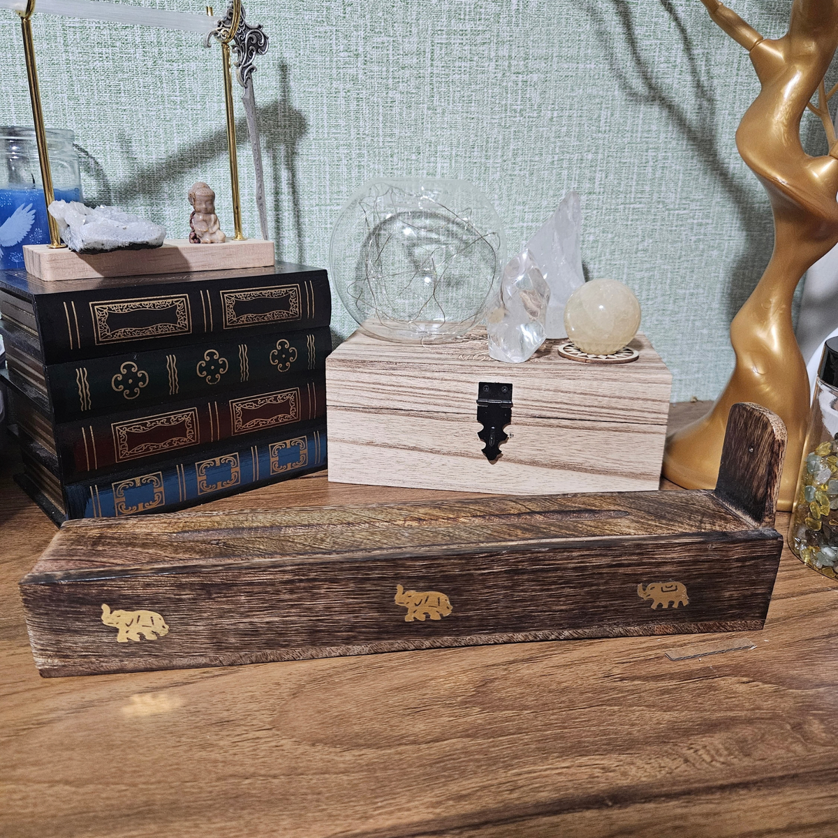Dark wooden incense stick holder and storage box decorated with small brass elephant inlays.