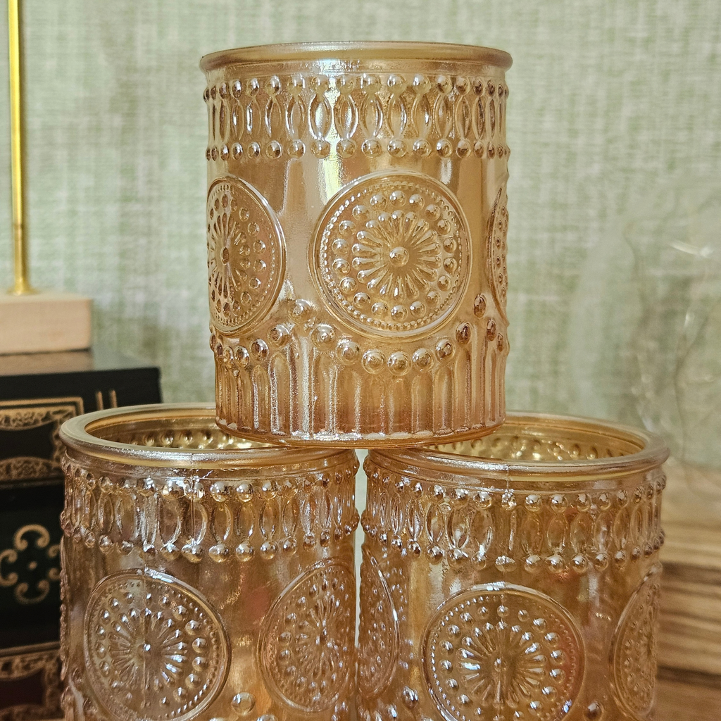 Close-up of amber glass tealight holders showing textured embossed pattern