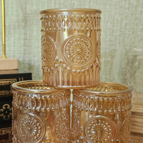 Close-up of amber glass tealight holders showing textured embossed pattern