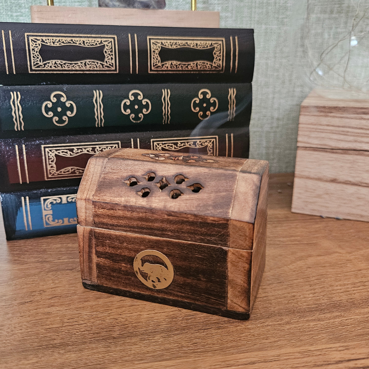 Close-up of rustic wooden incense cone holder with decorative smoke holes and brass-effect detail