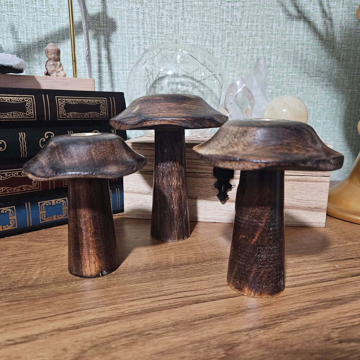 Set of three dark wooden mushroom-shaped incense cone holders in graduating sizes with brass-toned holders.