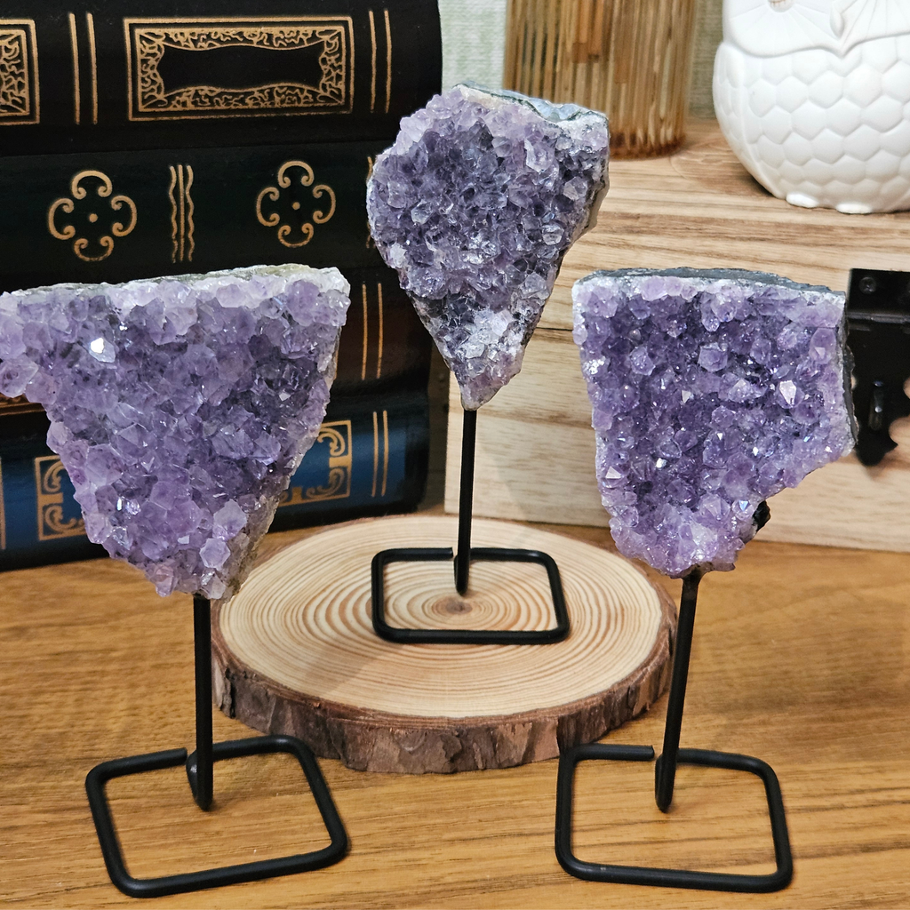 Natural purple amethyst druze crystal clusters displayed on individual metal stands