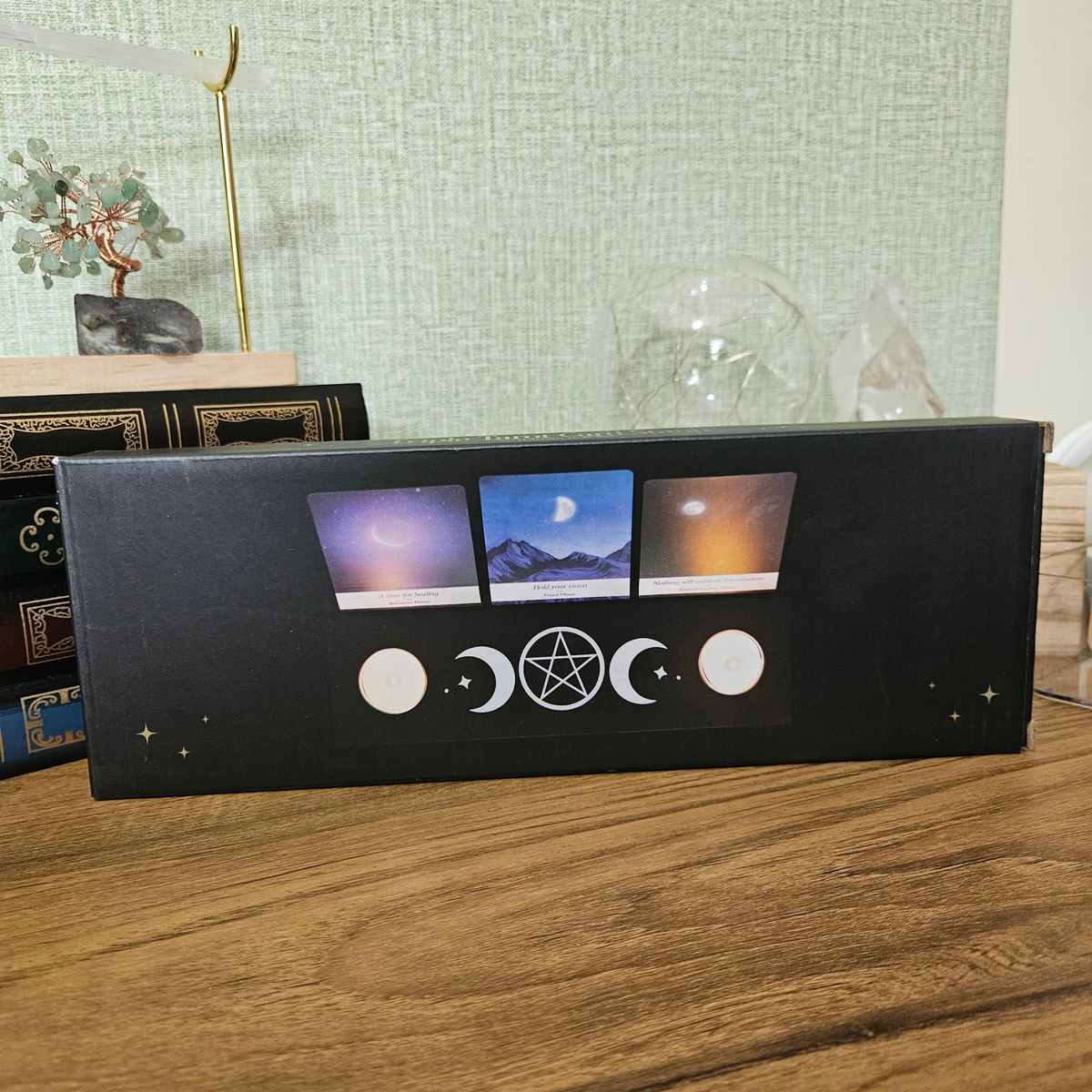 Black wooden Triple Moon tarot card holder with pentacle design, three tarot cards and two tealight holders.
