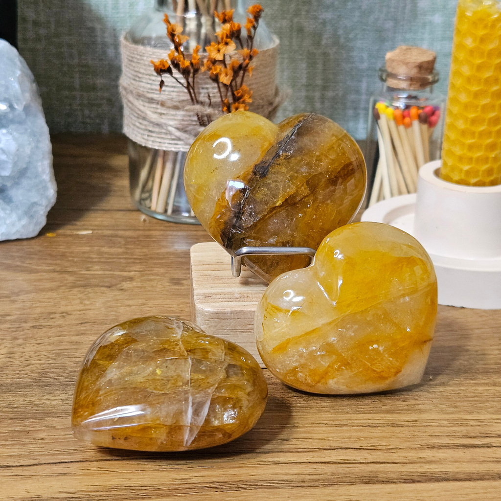 Three polished Golden Healer Quartz crystal hearts showing unique golden colouring and natural quartz patterns.