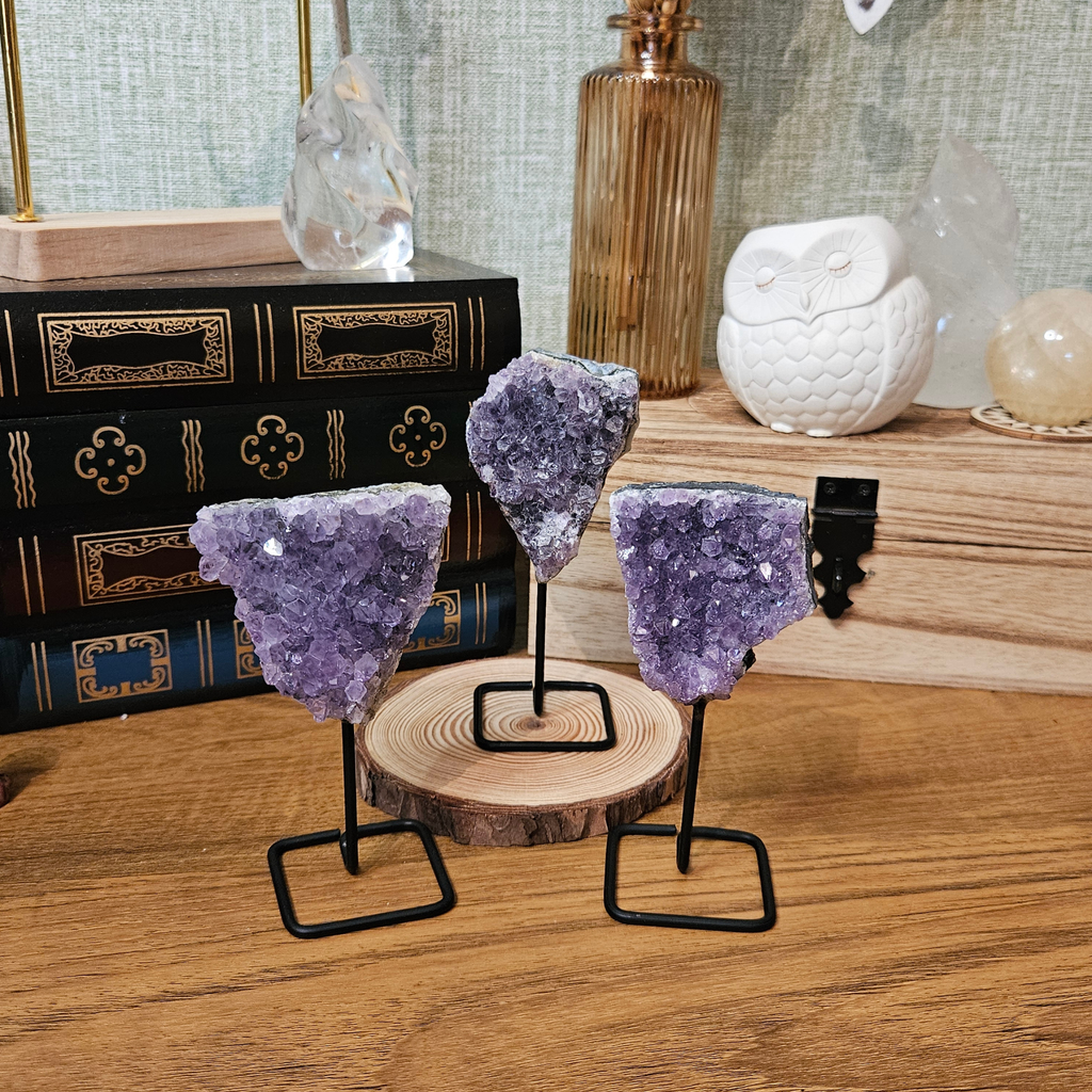 Natural purple amethyst druze crystal clusters displayed on individual metal stands
